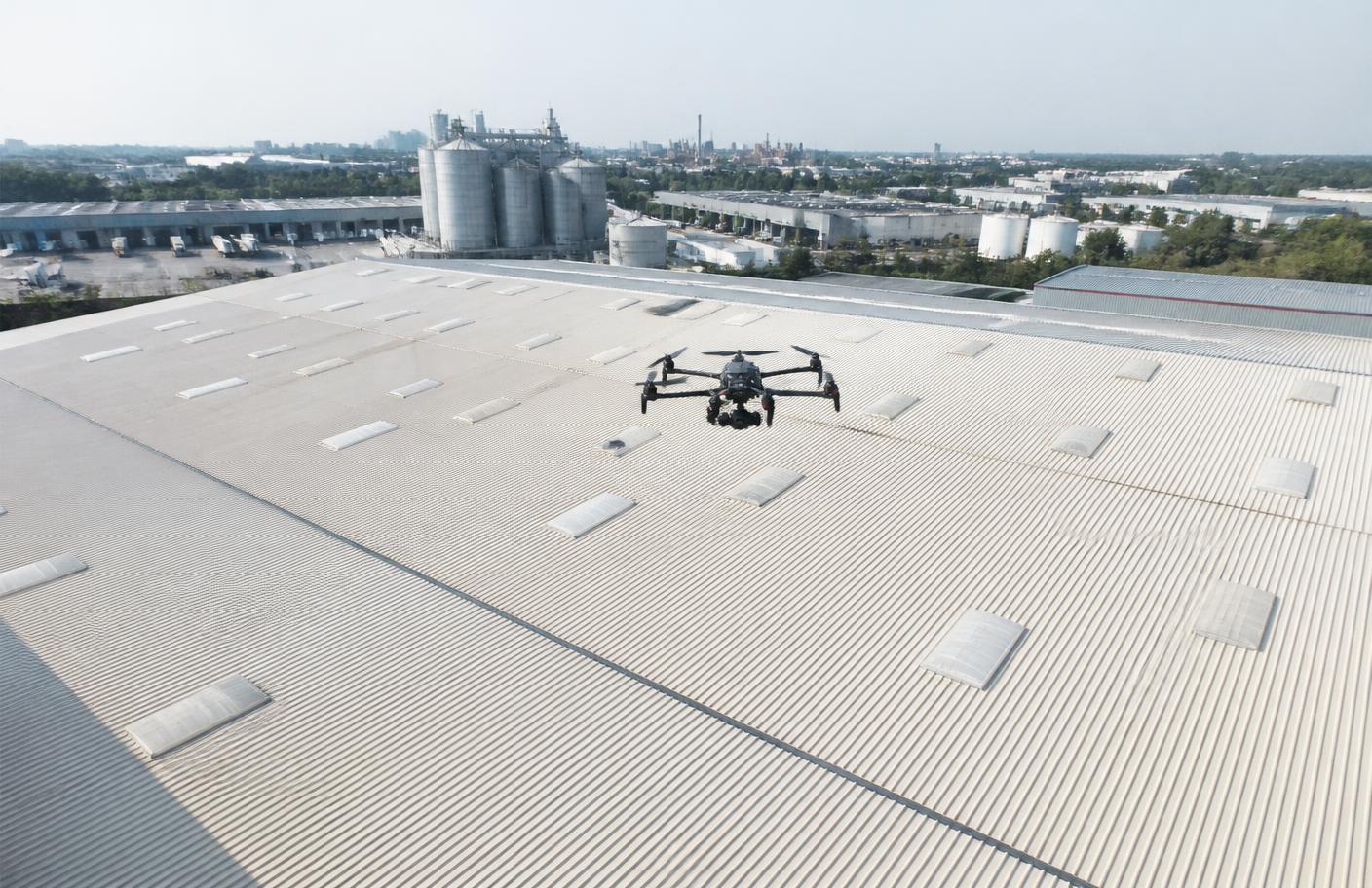 Drone inspecionando telhado de galpão em complexo industrial